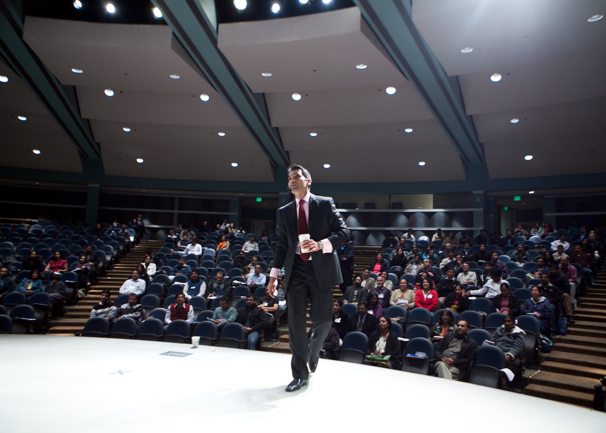 Srini Saripalli on stage with a large live audience